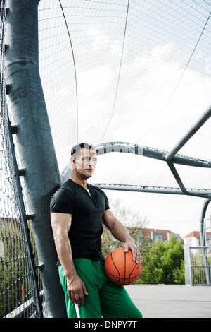 Porträt von reifer Mann steht auf Outdoor-Outdoor-Basketballplatz, Deutschland Stockfoto