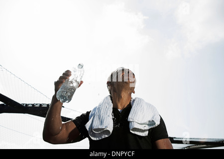 Reifer Mann mit Handtuch um den Hals, halten Sie die Flasche Wasser und blickte zu Himmel, Deutschland Stockfoto