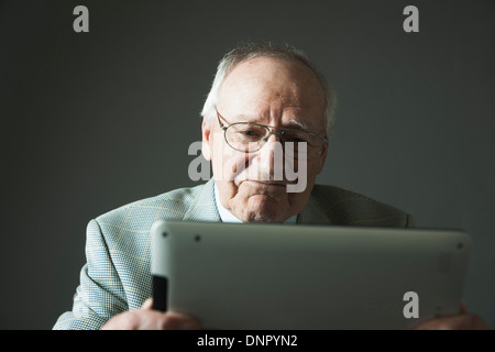 Älterer Mann mit Tablet-Computer im Studio Stockfoto