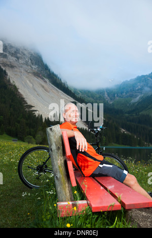 Reifen Sie Mann auf Bank See mit Mountainbike, Vilsalpsee, Tannheimer Tal, Tirol, Österreich Stockfoto
