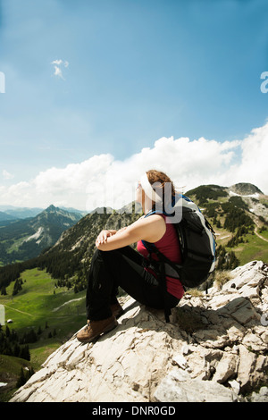 Reife Frau sitzen auf Klippe, Wandern in Bergen, Tannheimer Tal, Österreich Stockfoto