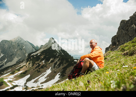 Reifer Mann sitzen auf dem Rasen, Wandern in Bergen, Tannheimer Tal, Österreich Stockfoto