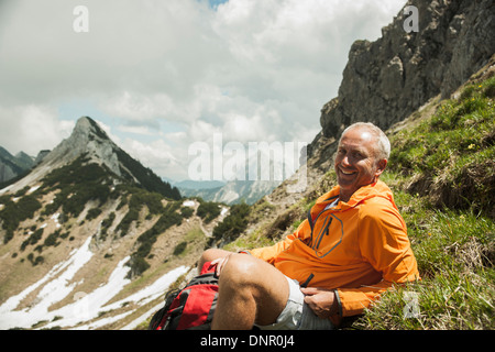 Porträt von reifer Mann sitzen auf dem Rasen, Wandern in Bergen, Tannheimer Tal, Österreich Stockfoto