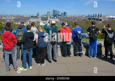 Gruppe von Jugendlichen Jungen Studenten auf Bildungsreise Greenwich Park & Hilltop Observatory mit Blick auf die Skyline von Canary Wharf London, England, Großbritannien Stockfoto