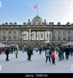 Erwachsene & Kinder Eisläufer mit Hintergrund historischen Somerset House Gebäude & Innenhof auf temporäre Winter Eislaufbahn Strand London, England, Großbritannien Stockfoto