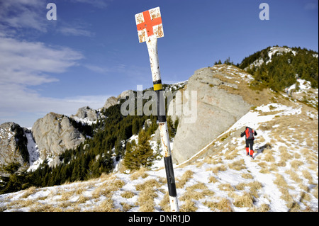 Rotes Kreuz-Markierung Pole auf einem Berg im Winter mit Wanderer im Hintergrund Stockfoto