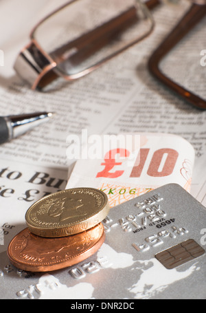 Gläser, Münzen, Kreditkarten und Banknoten auf Zeitungspapier. Makroaufnahme Stockfoto