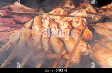 gebratenes Hähnchen am Spieß über Holzkohle in einem Rauch Stockfoto