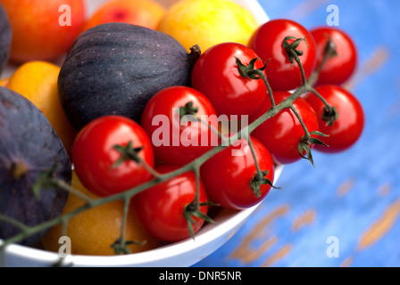 Strauchtomaten und Feigen in eine Schüssel geben Stockfoto