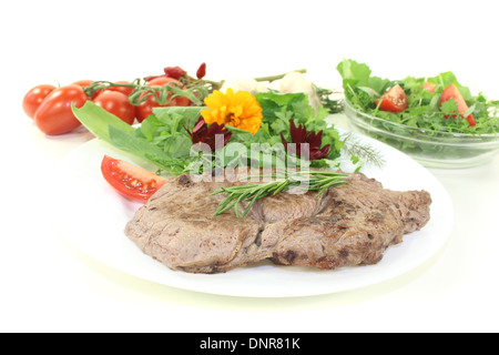 Gebratenes Rumpsteak mit Wildkräutersalat auf hellem Hintergrund Stockfoto