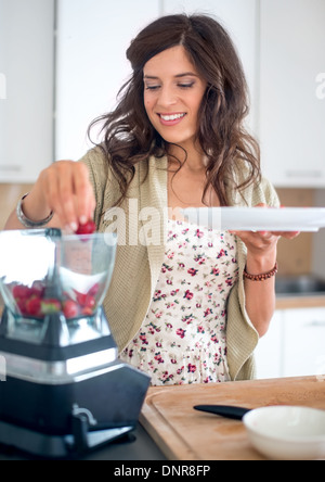 Attraktive Frau, die Vorbereitung der Früchte in den Mixer Stockfoto