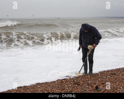 Portsmouth, England 4. Januar 2014. Eine Schatzsucher verwendet einen Metalldetektor suchen Strand für Objekte, die durch eine extrem hohe Gezeiten und große Wellen an Land gespült. Menschen haben zu bleiben weg von Küstengebieten wegen gefährlichen Bedingungen verursacht Überschwemmungen in vielen Bereichen empfohlen worden. Bildnachweis: Simon Evans/Alamy Live News Stockfoto