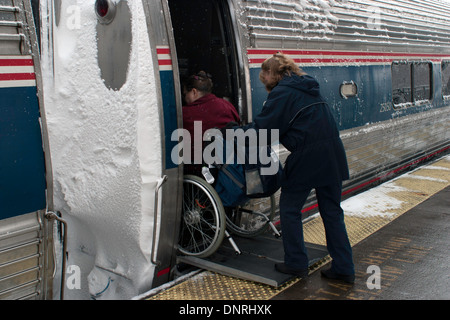 Angestellter Amtrack hilft ein Passagier-Board der Zug an einem stürmischen Wintertag. Stockfoto