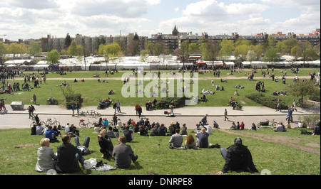 Sonnige Aussicht Menschen sitzen grasbewachsenen Hang, mit Blick über den Mauerpark auf Mauerpark Flohmarkt Stände, Berlin, Deutschland Stockfoto