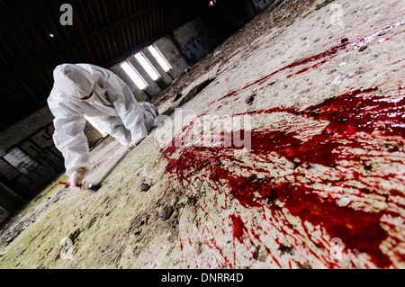 Szene des Verbrechens Officer (SOCO) untersucht eine Gegend um etwas Blut auf dem Boden [industrieübergreifend Modell] Stockfoto