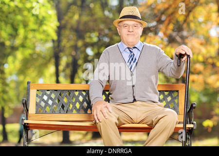 Entspannte senior Herrn saß auf einer Bank in einem park Stockfoto