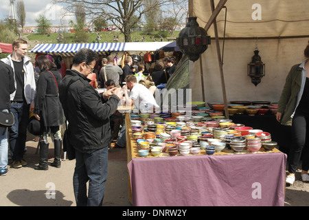 Sonnige Aussicht Mann in schwarzer Jacke Blick auf bunten Töpfen Marktstand und Menschen gehen, Mauerpark Flohmarkt, Berlin Stockfoto