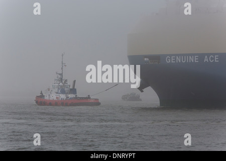 Ein Schlepper mit einem Frachter im Hamburger Hafen mit Nebel, Deutschland Stockfoto