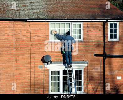 Ein Mann auf einer Leiter Fensterputzen England uk Stockfoto