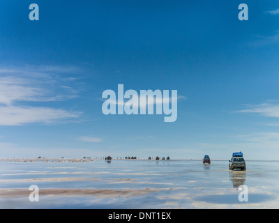 Touristen und Allrad-Fahrzeuge zu stoppen, sich zu beteiligen, das außergewöhnliche Zusammenspiel von Reflexionen aus dem Wasser am Salar de Uyuni. Stockfoto