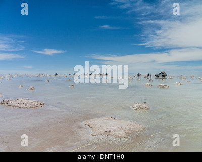 Touristen und Allrad-Fahrzeuge zu stoppen, sich zu beteiligen, das außergewöhnliche Zusammenspiel von Reflexionen aus dem Wasser am Salar de Uyuni. Stockfoto