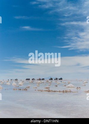 Touristen und Allrad-Fahrzeuge zu stoppen, sich zu beteiligen, das außergewöhnliche Zusammenspiel von Reflexionen aus dem Wasser am Salar de Uyuni. Stockfoto