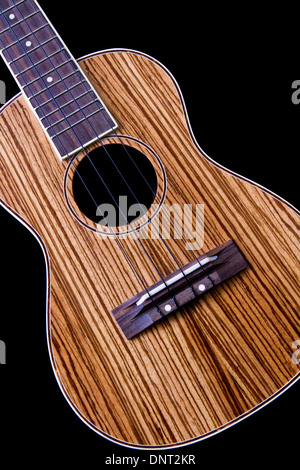 Eine Ukulele Akustikgitarre mit einer schönen Zebra Holz Spitze auf schwarzem Hintergrund isoliert. Stockfoto