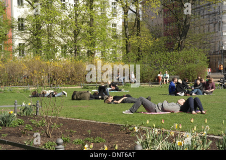 Sonnigen Stadtpark Blick Blume Bett Tulpen, junge Menschen lügen, entspannenden grünen Rasen, Bäumen und Gebäuden, Arkonaplatz, Berlin Stockfoto