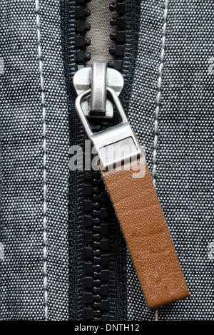 Fragment des offenen Kunststoff-Reißverschluss-Verschluss mit braunem Leder-tag Stockfoto