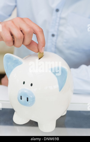 Nahaufnahme eines Mannes, Münze ins Sparschwein Mittelteil Stockfoto