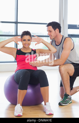 Trainer helfen Frau Bauch-Crunches auf Fitness-ball Stockfoto