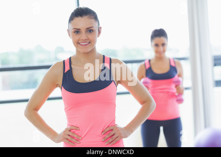 Lächelnde Frau mit Freund im Hintergrund im Fitnessraum passen Stockfoto