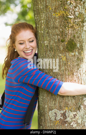 Lachend Rothaarige umarmt einen Baum Stockfoto