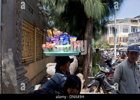 Eine Frau Essen Verkäufer trägt ein Tablett mit Snack auf ihren Kopf auf einer Stadtstraße in Phnom Penh, Kambodscha. Stockfoto