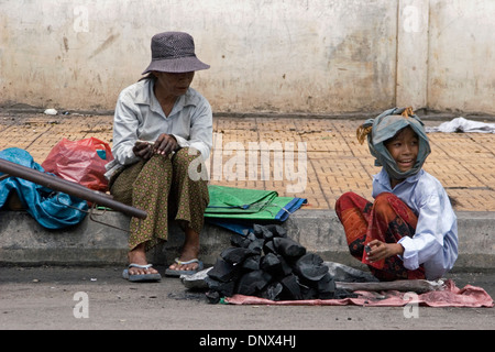 Eine Frau und ein junges Mädchen sind Holzkohle auf einer Stadt Straße in Phnom Penh, Kambodscha verkaufen sortieren. Stockfoto