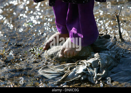 5. Dezember 2005; Balakot, PAKISTAN; Nachwirkungen des Erdbebens in Pakistan am 8. Oktober 2005. In Balakot geht ein junges Kind barfuß am Bach, wo viele der Damen waschen Sie ihre Kleidung und Geschirr. Obligatorische Credit: Foto von Nelvin Cepeda/San Diego Union T/ZUMA Press. (©) Copyright 2005 von San Diego Union T Stockfoto