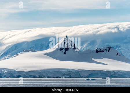 Antarktis - eine steile Gipfel steigt über den Surround Berg, während im Hintergrund Wolken eine noch höhere Gebirge in der gerlache Strait auf der Antarktischen Halbinsel verdecken. Stockfoto