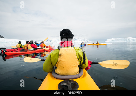 Kajakfahren zwischen Eisbergen Cuverville Island Antarktis // CUVERVILLE ISLAND, Antarktis — Ein aus einer Perspektive geschossenes Tandemkajak, das durch die stillen Gewässer zwischen Eisbergen auf Cuverville Island auf der Antarktischen Halbinsel gleitet. Diese immersive Perspektive fängt die ruhige Schönheit und Pracht der antarktischen Meereslandschaft ein und bietet einen einzigartigen Blick auf die eisige Umgebung vom Wasserspiegel aus. Stockfoto