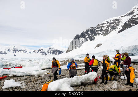 Antarktis - eine Gruppe von kajakfahrer nehmen einen shorebreak am felsigen Strand bei Cuverville Island auf der Antarktischen Halbinsel. Stockfoto