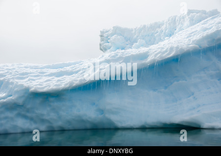 Antarktis - kleine Eiszapfen hängen von einem Felsvorsprung des Eisbergs. Stockfoto