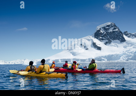 CUVERVILLE ISLAND, Antarktis – Kajakfahrer halten an, um die atemberaubende Landschaft an einem klaren, sonnigen Tag auf Cuverville Island auf der Antarktischen Halbinsel zu bewundern. Die unberührte Landschaft mit schneebedeckten Bergen, Gletschern und ruhigen Gewässern bietet eine atemberaubende Kulisse für diese Abenteurer, während sie einen der abgelegensten und schönsten Orte der Erde erkunden. Stockfoto