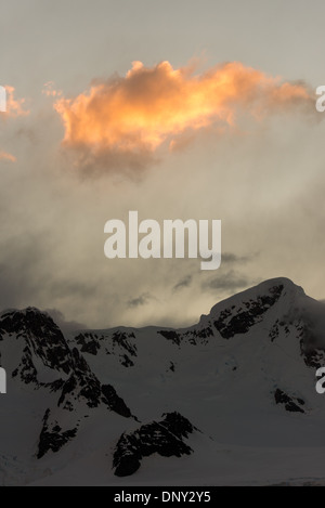 Antarktis - Letzte Sonnenstrahlen den Tag der goldenen Sonne eine Wolke über einem moutnain Bereich im Paradise Harbour, Antarktis. Stockfoto