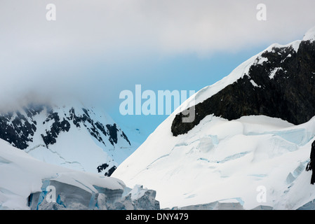 Lemaire Channel Mountains Antarktis // LEMAIRE CHANNEL, Antarktis — Schnee- und eisbedeckte Berge erheben sich dramatisch aus den Gewässern des Lemaire Channel entlang der Antarktischen Halbinsel. Diese Gipfel, die Teil des Kanals sind, der aufgrund seiner fotogenen Eigenschaften „Kodak Gap“ genannt wird, bieten eine der berühmtesten Ausblicke der Antarktis. Die steilen Bergmauern tragen dazu bei, den charakteristischen Charakter des Kanals zu erzeugen. Stockfoto