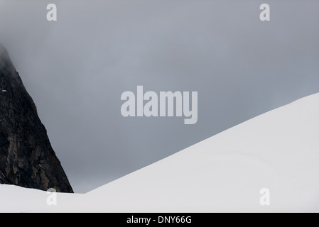 Lemaire Channel Mountains und Ice Antarktis // LEMAIRE CHANNEL, Antarktis — Schnee- und eisbedeckte Berge erheben sich dramatisch aus den Gewässern des Lemaire Channel entlang der Antarktischen Halbinsel. Diese Gipfel, die Teil des Kanals sind, der aufgrund seiner fotogenen Eigenschaften „Kodak Gap“ genannt wird, bieten eine der berühmtesten Ausblicke der Antarktis. Die steilen Bergmauern tragen dazu bei, den charakteristischen Charakter des Kanals zu erzeugen. Stockfoto