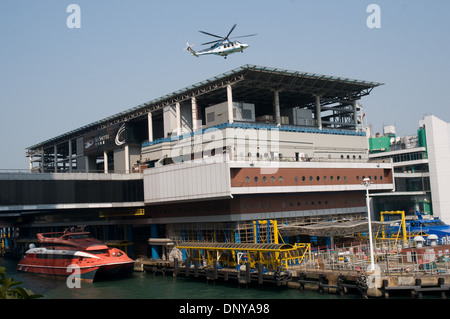 Ein Hubschrauber hebt ab vom Macau Ferry terminal Gebäude nach Macau zu fliegen. Neben dem Gebäude festgemacht sind die Fähren. Stockfoto