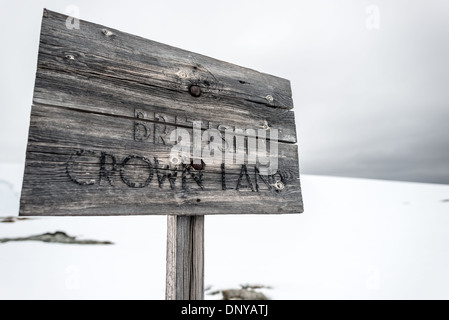 WINTERINSEL, Antarktis – Ein hölzernes Schild, das British Crown Land ausruft, steht in der Nähe von Wordie House, ursprünglich als Base F. bekannt, das Mitte der 1940er Jahre als Teil der britischen Mission Tabarin erbaut wurde. Das Haus wurde später nach James Wordie, dem Chefwissenschaftler der Antarktis-Expedition Ernest Shackletons, umbenannt. Sie ist in der Nähe der Vernadsky Forschungsbasis auf den Argentinischen Inseln erhalten. Stockfoto