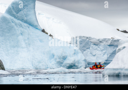 Antarktis - ein paar Kajakfahrer in einem Tandem kayak Navigieren einen schmalen Kanal zwischen großen Eisberge an Melchior Island auf der Antarktischen Halbinsel. Stockfoto