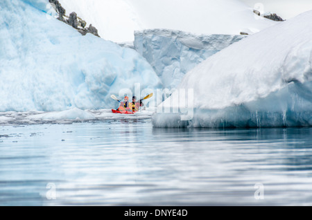 Antarktis - ein paar Kajakfahrer in einem Tandem kayak Navigieren einen schmalen Kanal zwischen großen Eisberge an Melchior Island auf der Antarktischen Halbinsel. Stockfoto