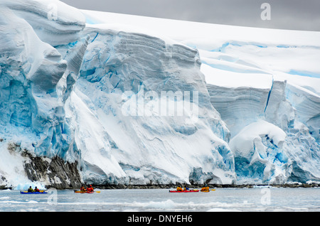 Antarktis - Kayaker paddeln an massiven Klippen von Gletschereis langsam Einschieben in die See entlang der Uferpromenade am Melchior Insel an der Westküste der Antarktischen Halbinsel. Stockfoto
