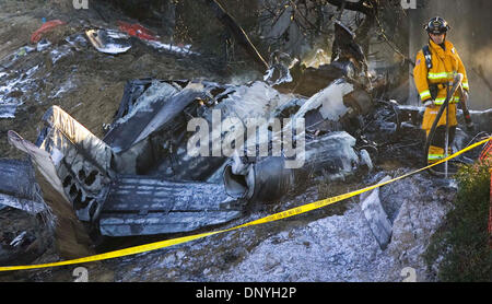 (Veröffentlicht 25.01.2006, b-1, NC-1, NI-1) NSPlaneCrash251648x001 ** CARLSBAD, CA. ** 24.01.06 - ein Feuerwehrmann steht neben den Trümmern der Twin Jet zweistrahligen Cessna 560, die stürzte und brach in Flammen während der Landung Dienstagmorgen auf McClellan-Palomar Airport in Carlsbad, Kalifornien, alle vier an Bord töten. Niemand auf dem Boden wurde verletzt. Die Jet-Engine Cessna 560 landete am McClella Stockfoto